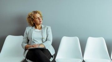 An older female worker ponders decision while sitting in waiting room