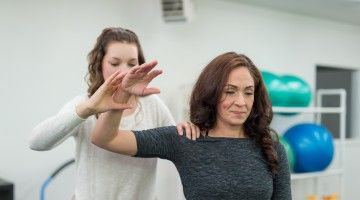 A physiotherapist helps client do arm exercises