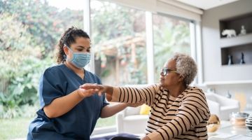 A homecare worker supporting her patient with her arm exercises