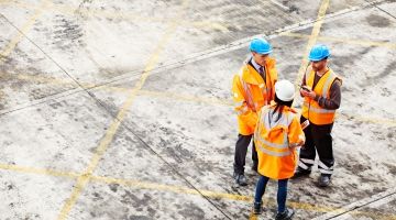 Three workers talking in a shipyard