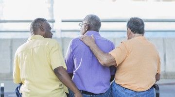 View from the back of three older men sitting on a bench