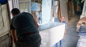 Two men lift heavy furniture off a truck