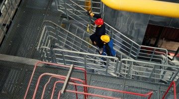 Overhead view of two people in safety helmets walking up the stairs in a plant