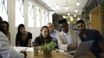 A group of diverse workers, including a worker with neurodiversity, in a well-lit office