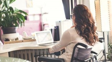 A woman in a wheelchair works from her home office