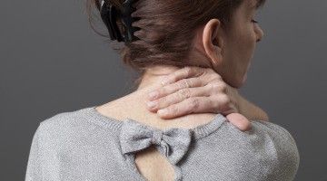 A view from the back of a woman holding her neck