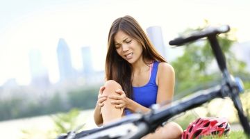 A woman grimaces after falling off her bike