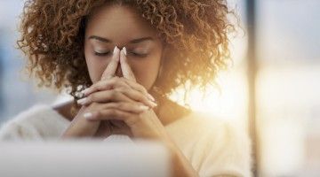 Woman rests face in hands at laptop