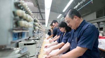 Workers on an assembly line in an embroidery factory do repetitive work
