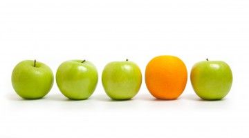 Four green apples with one orange in a row