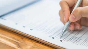 Close-up of hand holding pen filling out survey