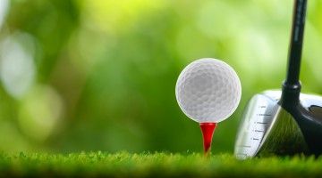 Close-up of a golf ball on red tee and head of a one wood golf club