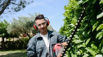 Young landscaping worker holds hedge trimmer