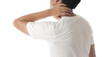 Man in white t-shirt holds neck