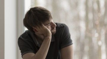 A man sits leaning staring out the window