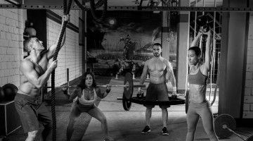 A black and white image of men and women lifting weights
