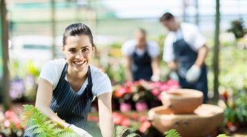 Smiling greenhouse owner working with plants