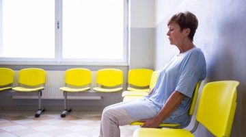 A downcast woman sits waiting for news in an empty waiting room