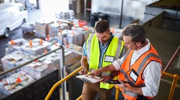 Two warehouse worker discussing report