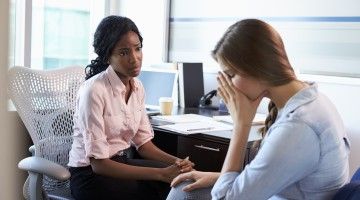 Woman consoling sad female co-worker