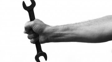 A black and white image of a wrist gripping a tool