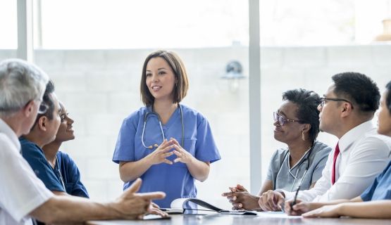 Members of a hospital committee listen to presentation by female health care worker