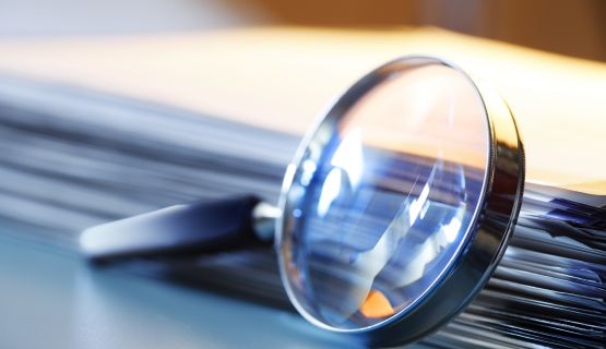 A magnifying glass rests against a stack of papers