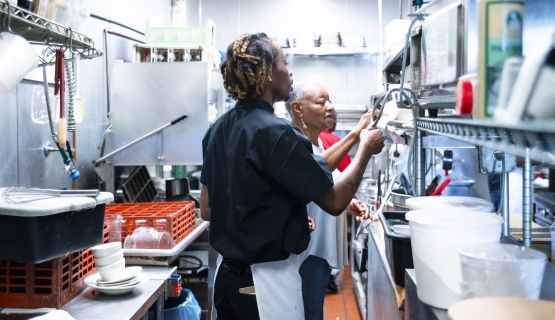 Two workers in a restaurant kitchen.
