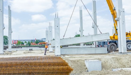 A worker guides a crane lifting concrete at a construction site