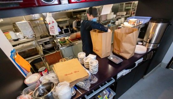 Masked restaurant worker prepares take-out food orders