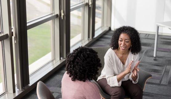 Two women sharing a confidence at work