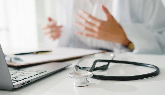 An out-of-frame doctor talks to someone on a laptop screen