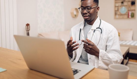 A young male doctor engaging in an online discussion using his laptop