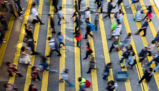 Overhead image of fast-moving pedestrians using a crosswalk to cross a road.