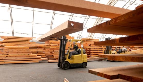A worker drives a forklift in a lumber mill