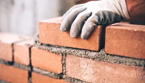 Gloved hand laying bricks Thumbnail