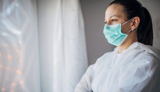 A health-care worker wearing a face mask and body covering