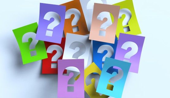 13 colourful cardboards, each with a question mark cut-out in the middle, overlap each other in a pile