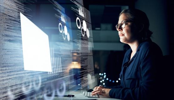 A woman studies data and charts projected on a screen