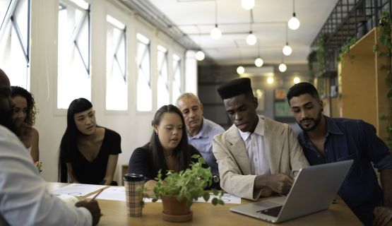 A group of diverse workers, including a worker with neurodiversity, in a well-lit office
