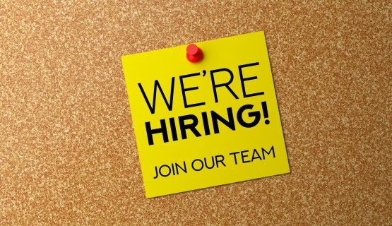 A yellow note tacked on a cork board reads: "we're hiring! join our team"