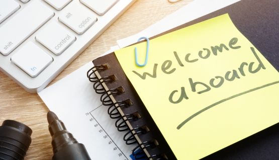 Sticky note clipped to a notebook reads "welcome aboard"