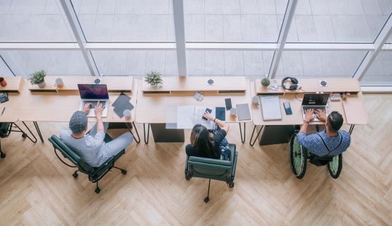 Three workers in a modern office, one using a wheelchair.