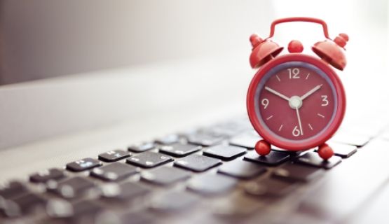 An alarm clock sits on a computer keyboard.