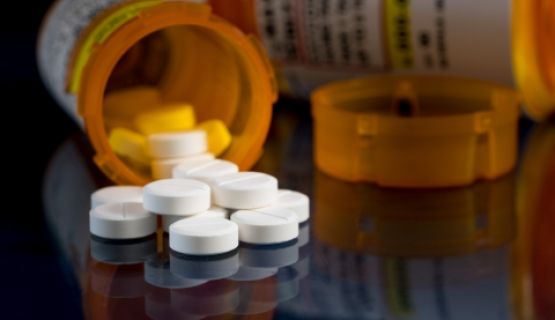 A bottle of pills spilled on a table.