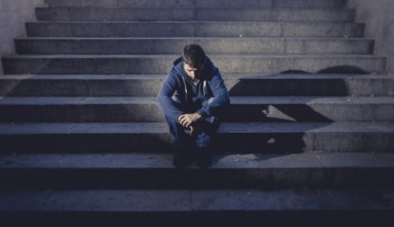 A man sits on a dimly lit staircase.