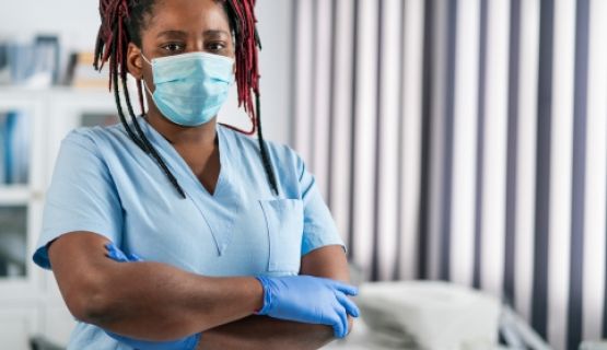 A masked personal support worker looks grimly at the camera