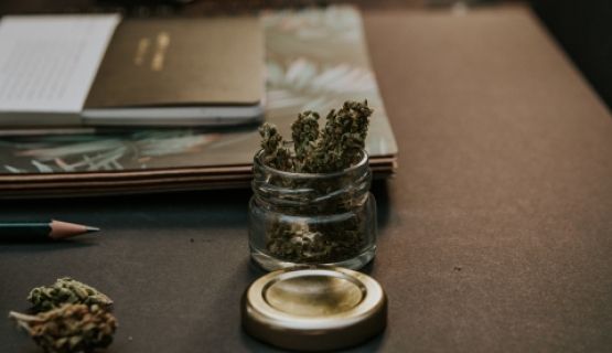 A jar of cannabis buds on a brown desk
