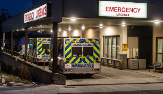 Two ambulance parked at the emergency entrance of a hospital in the night