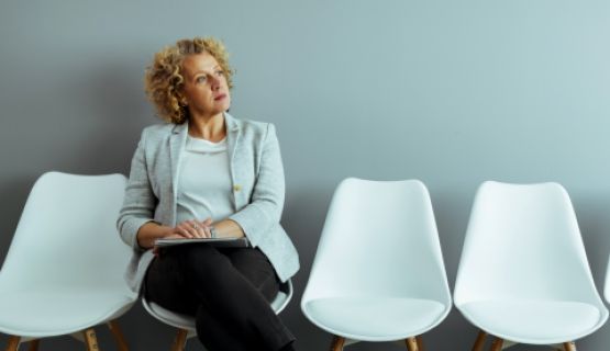 An older female worker ponders decision while sitting in waiting room